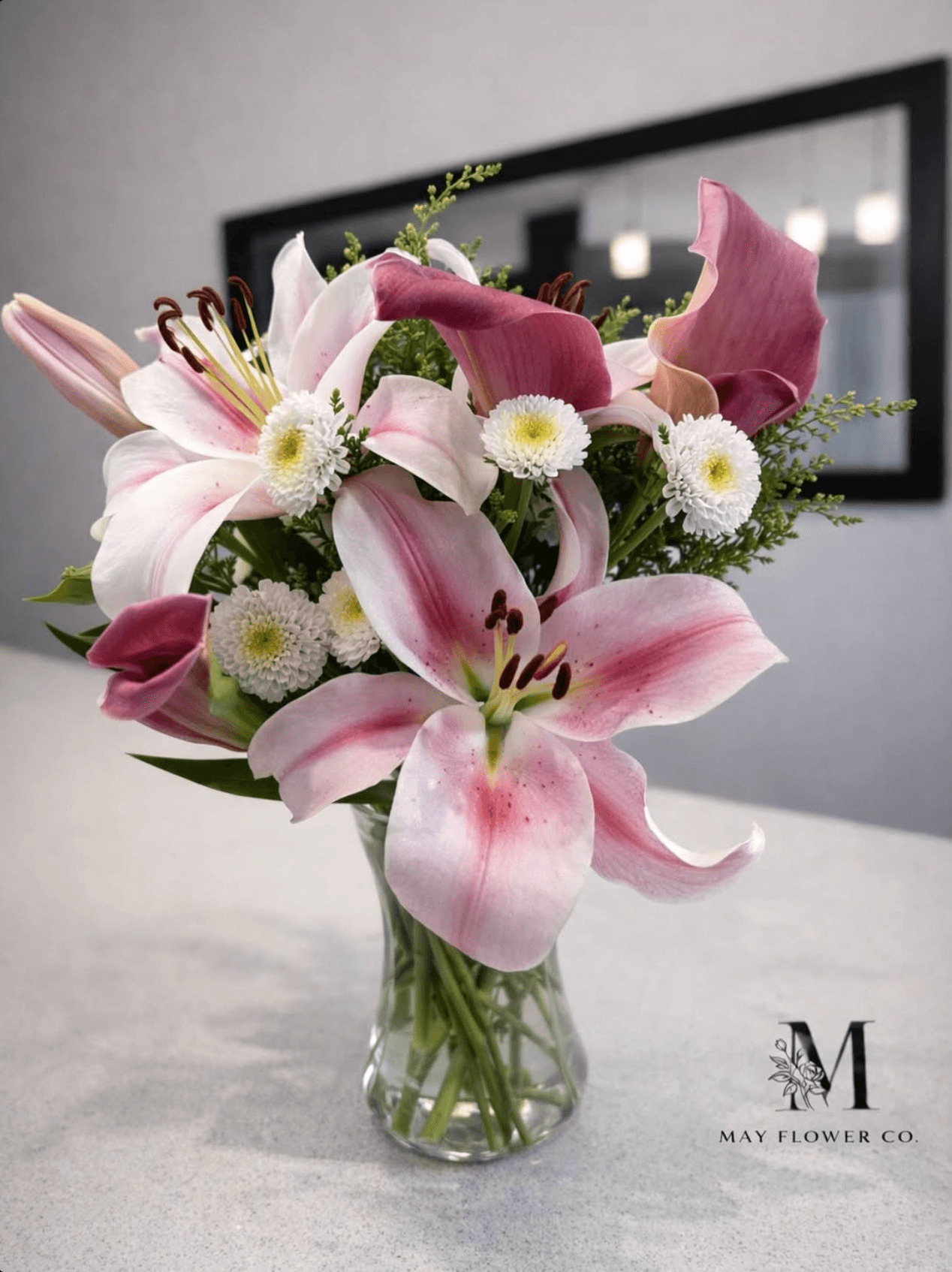 A quiet arrangement of pink lilies and seasonal blooms suitable for sympathy.