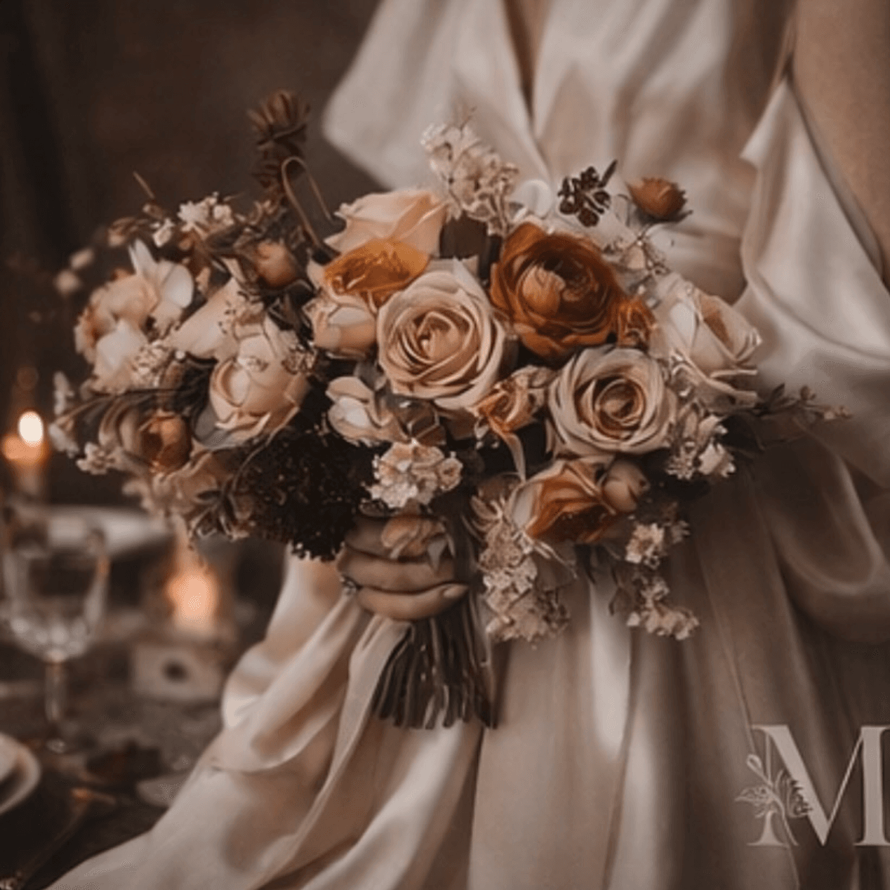 A bride in ivory holds a bouquet of cream roses and dried stems by candlelight.