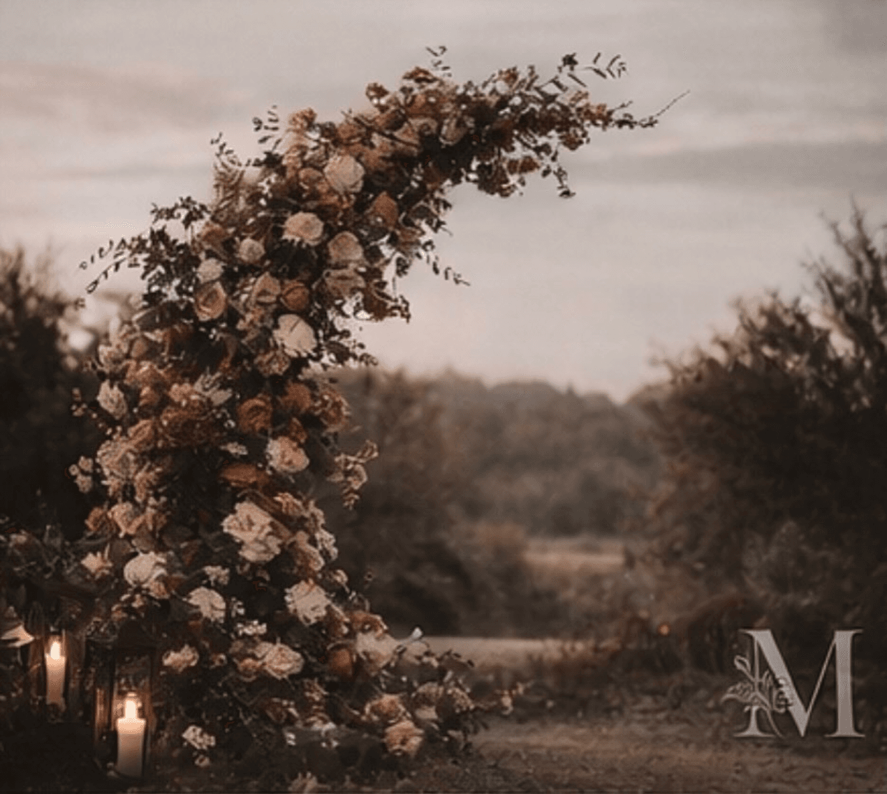 A ceremony arch at dusk in an open field.